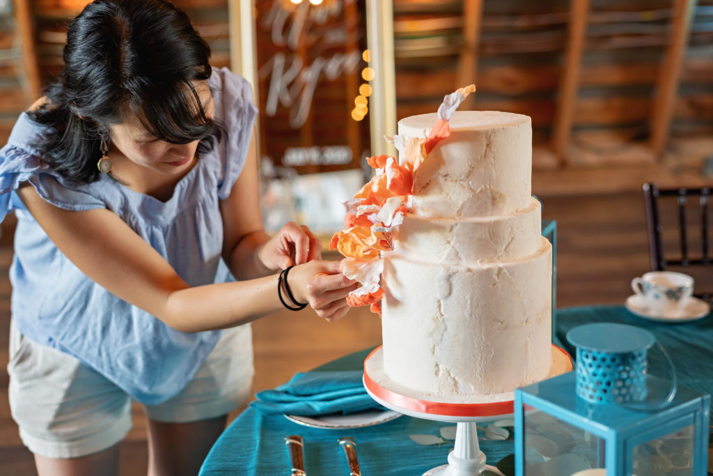warrenton baker decorating a wedding cake with orange sugar flowers