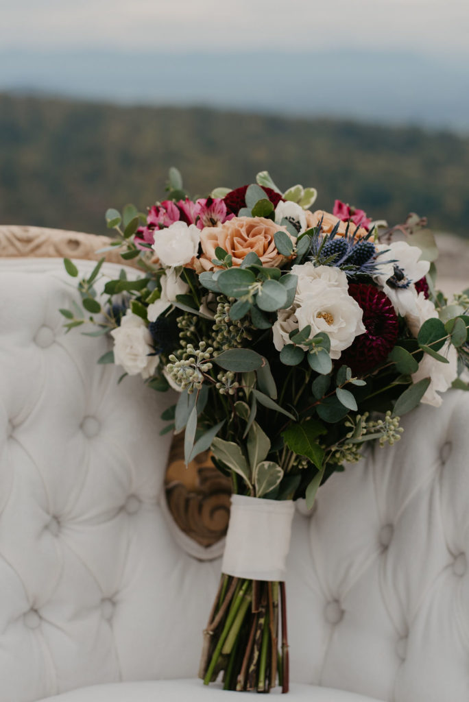 bridal bouquet on vintage chair with eucalyptus, dahlias, Panda Anemone, Blush ranunculus, Café Latte Copper Garden roses, plum Alstroemeria, Bells of Ireland, Verigated ivy and Maidenhair fern
