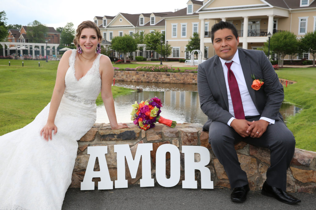 bride and groom outside regency at dominion valley wedding with the sign amor