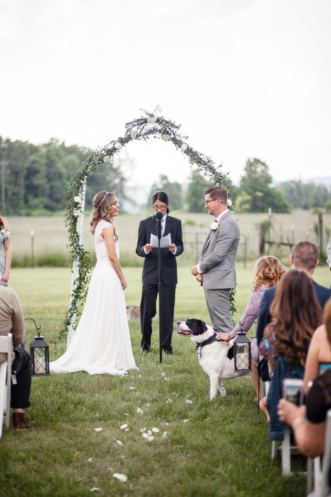 Outdoor ceremony with iron arch and flower garland at East Lynn Farm Pine Grove