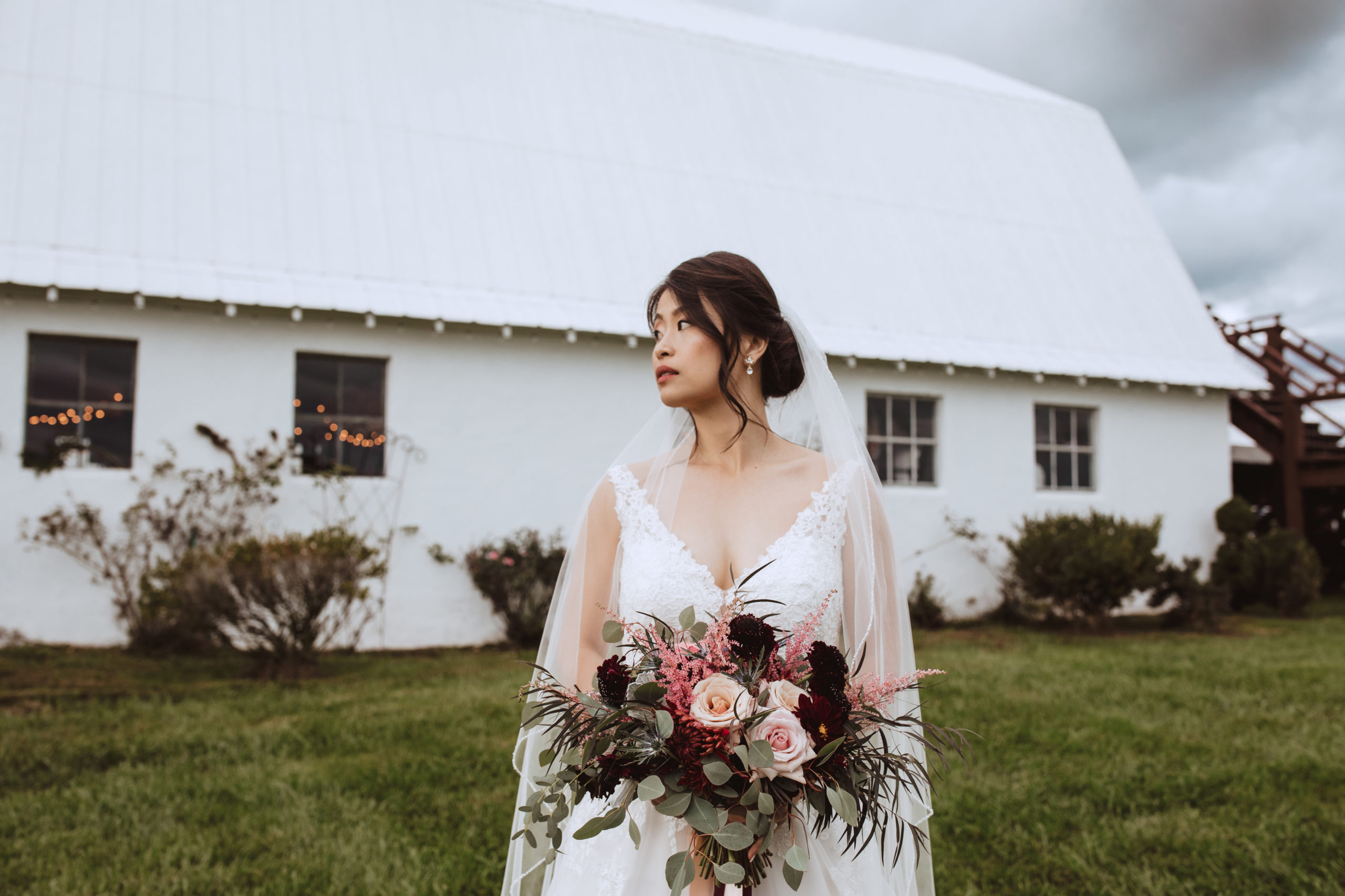 bride holding bridal bouquet behind barn