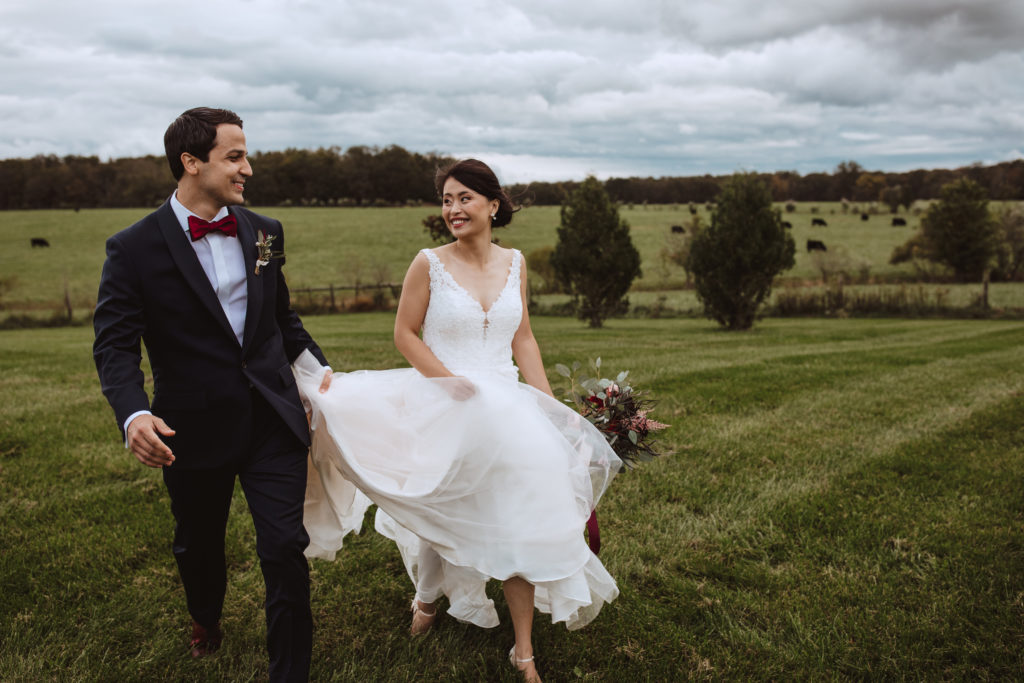bride and groom smiling and running in the farm lawn