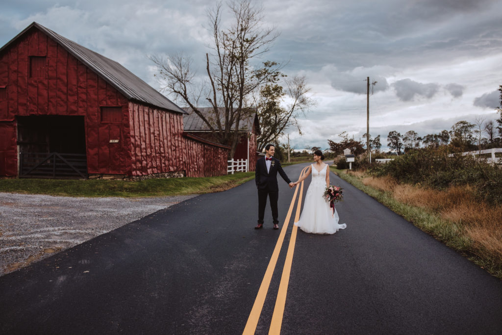 bride and groom holding hands in the middle of the road