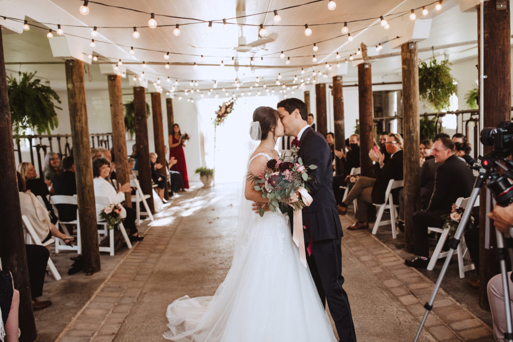 bride and groom kissing in the ceremony aisle. Bride is holding a bouquet