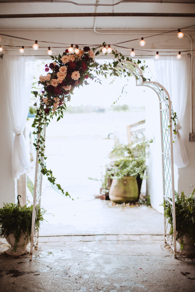 wedding ceremony arch with cluster of fall flowers on the side