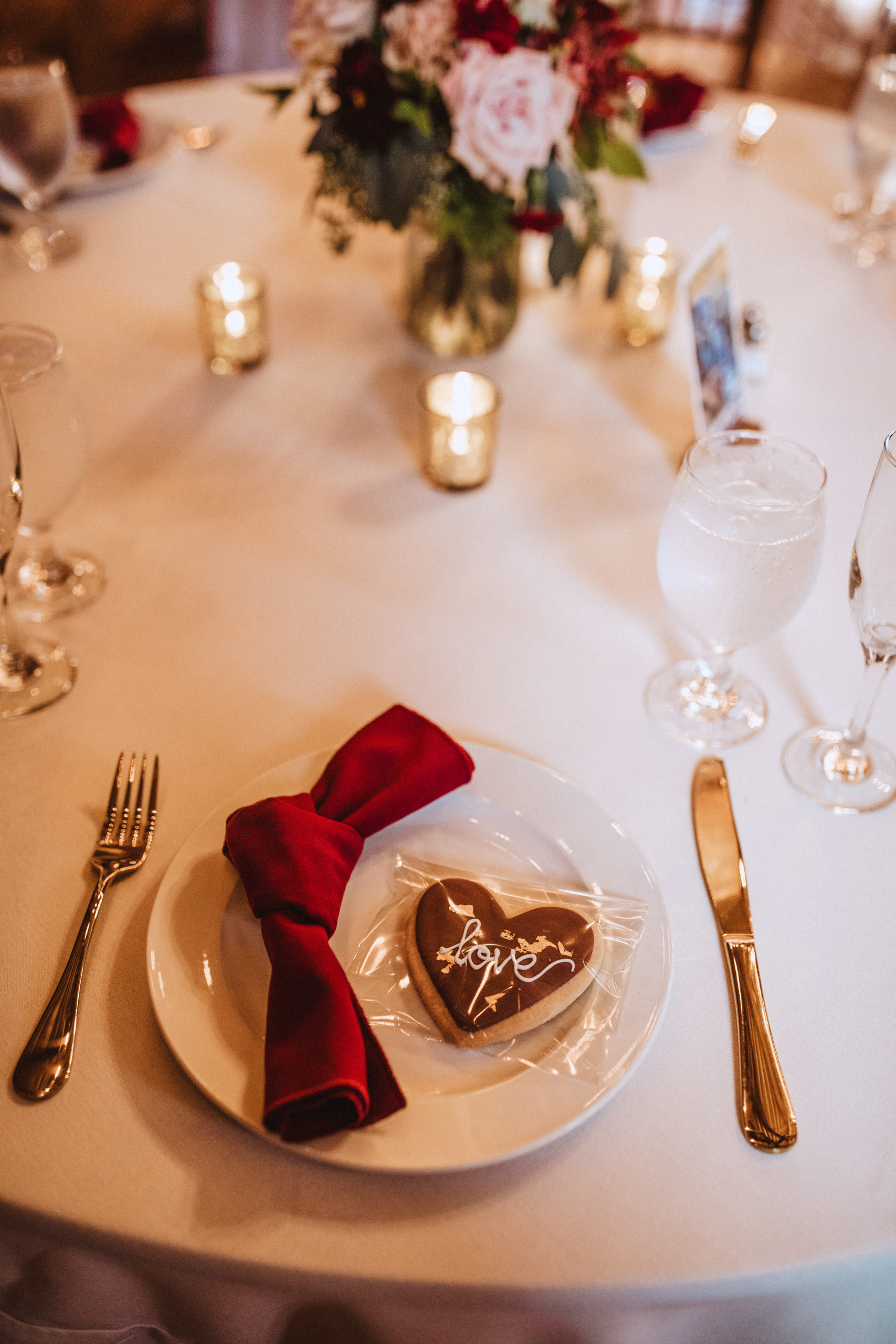 tablesetting with white plate, burgundy knotted napkin with love cookie as a favor