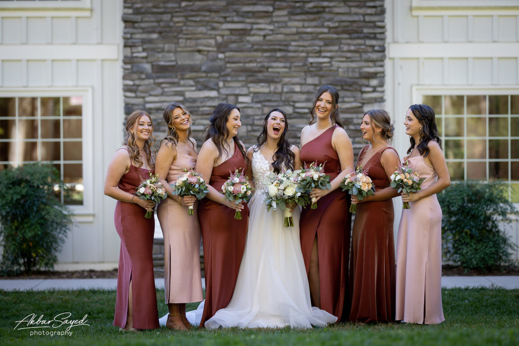 The bride with the Bridesmaids smiling holding their bouquets.